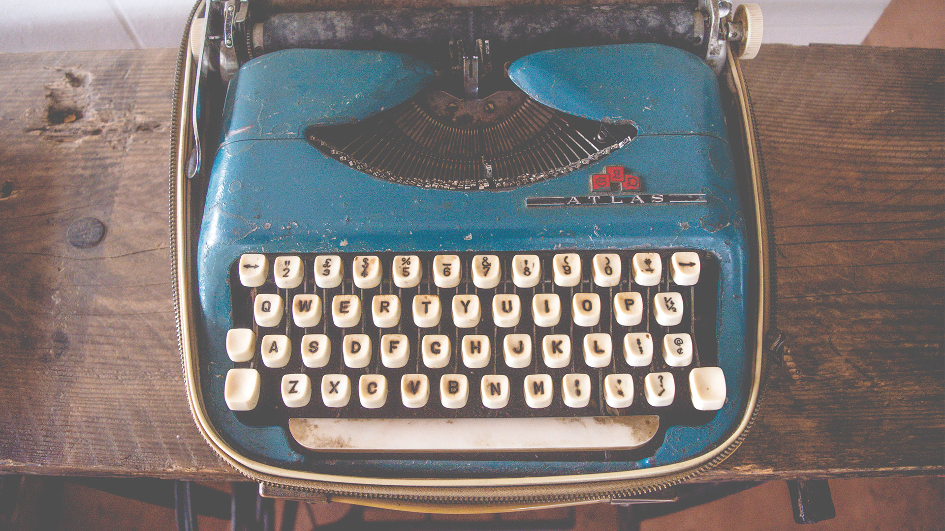 a blue typewriter on a wood desk