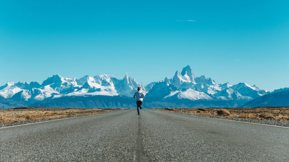a person running on a flat road towards the mountains