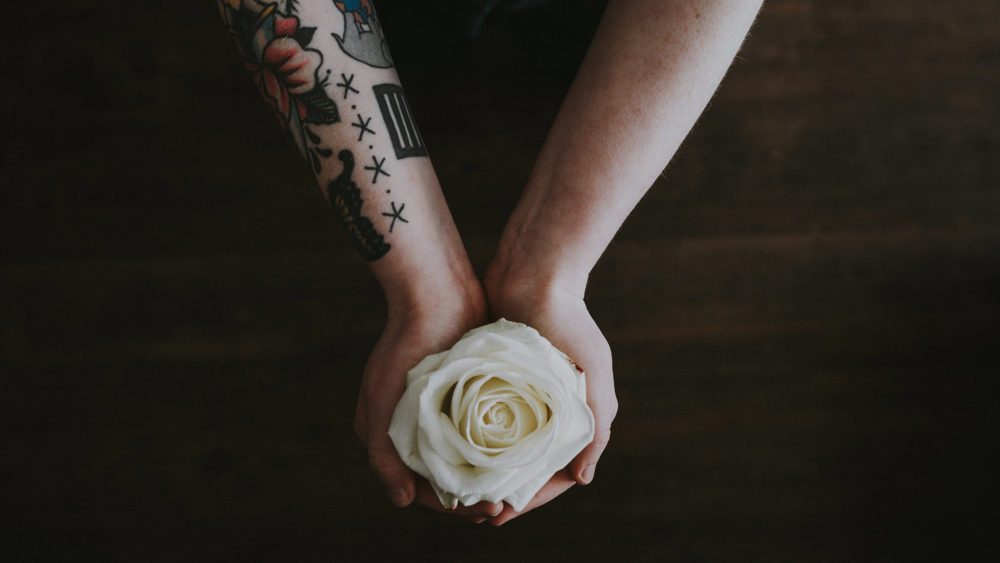 a person holding a white rose in their hands